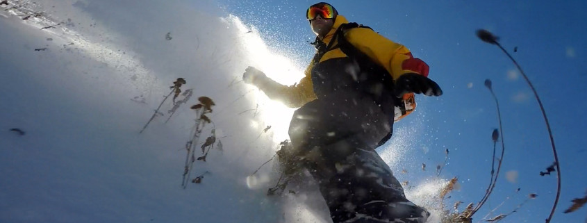 Jeremy Jensen surfing thru the snow and weeds without any bindings on his Grassroots Powsurfer